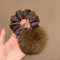 Striped knit scrunchie with a large brown pompom fluff accessory held in hand - Pom Pom Hair Tie