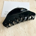 Dettaglio di una grande pinza per capelli nera lucida su sfondo di marmo per capelli folti - L Nero