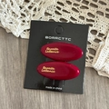 Dettagli di due fermagli per capelli in acetato rosso vino con logo dorato su carta - Stile Ovale Rosso Vino