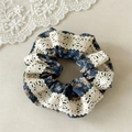 Dettaglio di scrunchie floreale blu scuro con bordo in pizzo crema e trama in tessuto retrò - Elastico in Pizzo Blu