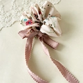 Détail d'un chouchou rose à fleurs avec de longs rubans sur fond de dentelle crème - Noeud Rose