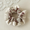 Dettaglio di uno scrunchie floreale con bordi in pizzo su uno sfondo cremoso - Elastico in Pizzo Rosa