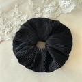 Détail d'un chouchou noir avec texture plissée élégante sur fond de dentelle blanche - Velours Plissé Noir