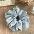 Vue détaillée du chouchou bleu clair avec motifs argentés sur un tissu doux plissé - Bleu