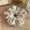 Détail d'un chouchou abricot doux avec paillettes argentées sur fond de bois naturel - Champagne