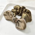 Dettaglio scrunchie in seta marrone oliva con fiocco a righe su un piatto bianco - Verde militare