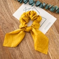Ginger yellow silk-textured scrunchie with long ribbon streamers on wood background - Yellow