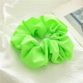 Primo piano di un elastico per capelli verde neon in tessuto opaco su sfondo bianco - Verde limone