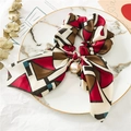 Détail d'un chouchou aux motifs géométriques avec un grand nœud et un pendentif en perle - Tricot à Motif Blocs Rouges