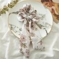 Detail of white floral ribbon scrunchie with purple flower patterns on marble tray - White Floral