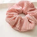 Close-up of pink satin scrunchie with pleated texture on a white decorative tray - Pink