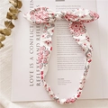 Close-up of a white bunny ear headband with red paisley print on a magazine - Colorful White