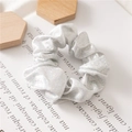 Macro shot of silver glitter scrunchie with metallic shine on minimalist background - White