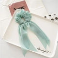 Detail of mint green chiffon hair scrunchie with long ribbons on minimalist white tray - Green