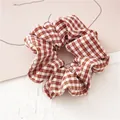 Detailed close-up of brown and white checkered fabric scrunchie with soft woven texture - Coffee Plaid