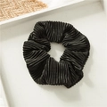 Elegant black pleated satin scrunchie placed on a minimalist white wooden tray for hair styling - Black