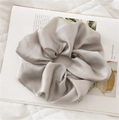Close-up of elegant silver grey satin scrunchie with soft silk texture and pleats - Gray