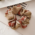 Close-up of checkered fabric hair scrunchie with soft plaid texture and elastic ruffles - Light Coffee
