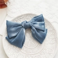 Close-up of double-layered blue mesh bow hair clip with central knot detail on porcelain - Blue