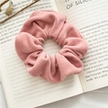 Elegant pink textured fabric scrunchie with soft velour finish on an open book - Pink
