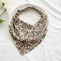 Dettaglio di un foulard floreale vintage con fascia elastica su piatto decorativo - Verde