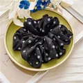 Primer plano de un coletero grande de gasa negra con lunares blancos en una bandeja - Estilo de Lunares Negros