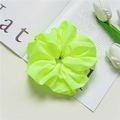 Detail view of a bright neon green chiffon scrunchie on a stylish fashion magazine - Green
