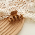 Detail of caramel resin hair claw clip with glossy finish on a decorative lace tray - Khaki
