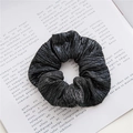 Chouchou noir métallisé avec texture plissée posé sur un livre ouvert élégant - Noir