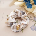Detailansicht eines floralen Scrunchies auf Vintage-Papier mit Trockenblumen-Dekor - Satin Blumen Weiß