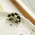 Close-up of black and white checkered hair claw clip on a decorative ceramic plate - Hollow Semicircle