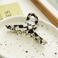 Detail of checkered hair claw clip on ceramic tray with minimalist aesthetic props - Crossed