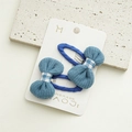 Dettaglio di fermagli per capelli in maglia blu con fiocco a quadretti su carta - Blu