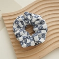 Detail eines blau-weiß karierten Haargummis mit Blumenmuster auf einem Holztablett - Sonnenblume Marineblau