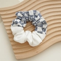 Detail eines blau-weiß karierten Stoff-Haargummis mit Blumenmuster auf einem Holztablett - Sonnenblume Marine Patchwork