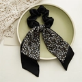 Detail eines schwarzen Satin-Haargummis mit floralem Band auf Keramikteller - Floral Schwarz Doppelte Streamer