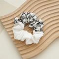 Nahaufnahme von Frühlings-Stoff-Haargummi mit Gänseblümchen-Print und weißen Falten-Details - Sonnenblume Schwarz und Weiß Patchwork