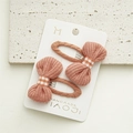 Detail of two handmade orange knit bow hair clips on a white presentation card - Caramel color