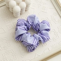Dettaglio dell'elastico per capelli a quadretti viola su un vassoio color crema - Houndstooth