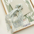 Detail of floral chiffon scrunchie with long ribbons on a minimalist background - Blue Floral Streamer