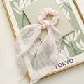 Detail eines rosa karierten Haargummis mit weicher Faltenstruktur und Schleife - Gingham Band Rosa