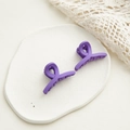Dettaglio di due mollette per capelli a spirale viola opaco su piatto decorativo - Stile Papillon / Viola