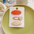 Detail of 3-piece kids hair clip set with orange fabric and pink heart on a green plate - Orange Heart Set