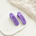 Dettaglio di due piccole mollette per capelli blu opaco su espositore in pietra - Stile Tondo E Rettangolare / Viola