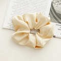 Pale yellow satin scrunchie with silk texture on a white table with a magazine - Satin Cream Yellow