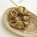 Detailed shot of a classic plaid fabric scrunchie with yellow and red patterns in a basket - Yellow Plaid