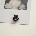 Close-up of a 2cm mini translucent floral hair claw clip on an artistic card - Caramel color