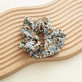 Makro-Detail von Blumen-Haargummi mit blau-orangen Blüten auf einem Holztablett - Blau Einzelne Schleife