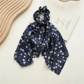 Close-up of dark blue floral chiffon scrunchie with long ribbons on a vintage book - Dandelion Navy Blue