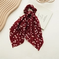 Close-up of elegant burgundy floral fabric hair scrunchie with long ribbons on wooden stand - Dandelion Red